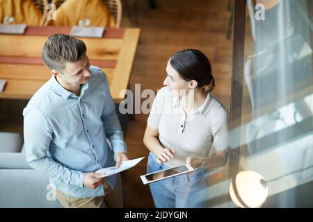 Above view of cheerful young marketing specialists standing in modern cafe and sharing product promotion ideas Stock Photo