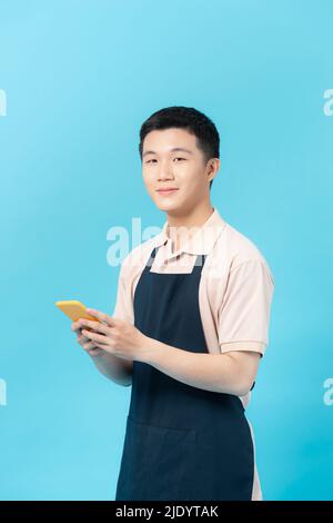 Barber man in an apron sending a message with the mobile Stock Photo