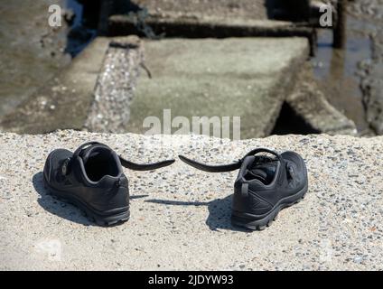 The abandoned shoes at the rim of the ending of a demolished way Stock Photo