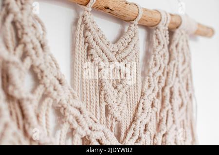 Wall decor in the style of weaving macrame handmade from beige natural threads on a white background Stock Photo