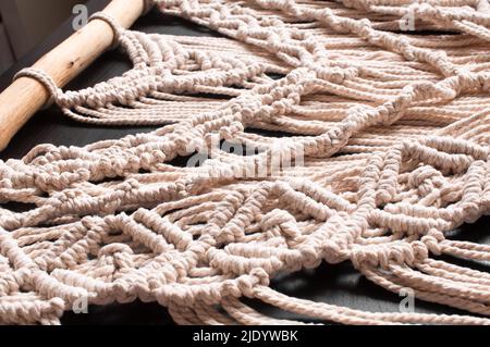 Part of the decor in the style of weaving macrame handmade from beige natural threads on a black background Stock Photo