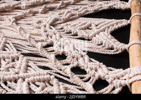Part of the decor in the style of weaving macrame handmade from beige natural threads on a black background Stock Photo