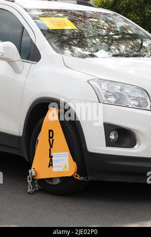 uninsured or untaxed vehicle clamped by roadside Stock Photo