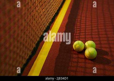 Close-up of three yellow tennis balls placed in shadow of net on court, tennis game concept Stock Photo