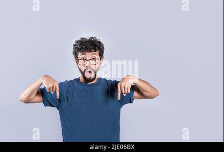 Handsome man pointing down, surprised guy pointing his fingers down, amazed young man pointing down Stock Photo