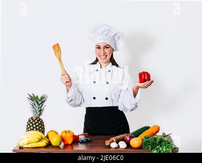 Woman chef holding a ladle on a table with vegetables, A smiling woman chef holding a ladle and vegetables, portrait of a woman chef holding a ladle Stock Photo