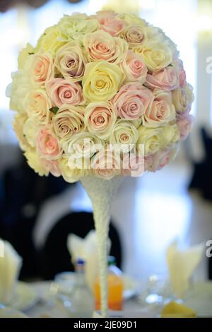 Perfectly round floral centerpiece featuring an exquisite pastel color roses bouquet, beautiful flower heads mounted on a tall and thin support Stock Photo