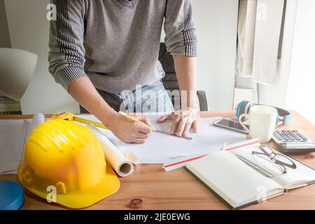 Architect designing on table in office,Vintage,Sunset light,Yellow safety hard hat Stock Photo