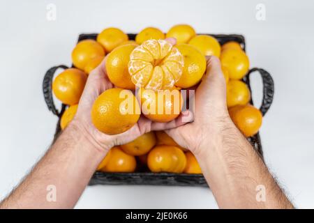 Man hands holding fresh and tasty tangerines on isolated white background. Stock Photo
