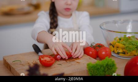 Young Girl Vlogger Making Social Media Video About Cooking At Home, looking on smartphone on tripod. episode about healthy eating. concept of attraction children to healthy diet of early age Stock Photo