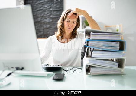 Stressful Afro  Businesswoman Sitting In Office With Stacked Of Files Stock Photo