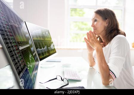 Stock Market Analyst At Office Desk Using Multiple Screens Stock Photo