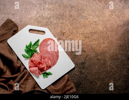 Meat food sausage salami slices on cutting board on aged brown background, mockup Stock Photo