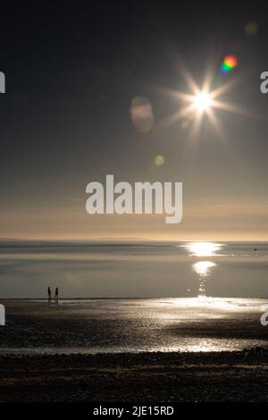 Sun and couple on the West Shore beach, Llandudno, North Wales Stock Photo