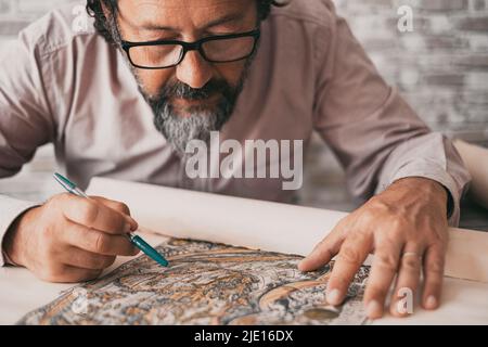 Close up portrait of man busy studying a paper design map on the desk table. Professional worker activity. Mature people working concentrated. Wearing Stock Photo