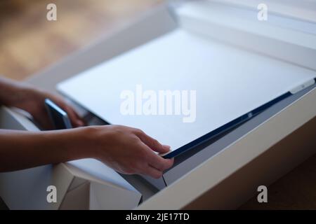Tbilisi, Georgia - May 25, 2022: Woman removes white protective film from New iMac monitor Stock Photo