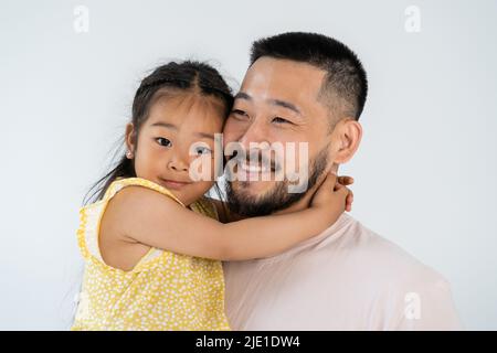 cheerful asian daughter hugging happy father isolated on grey Stock Photo