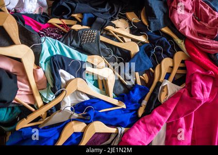 Lots of clothes on hangers piled in a pile. Heap of used clothes. Second hand for recycling Stock Photo