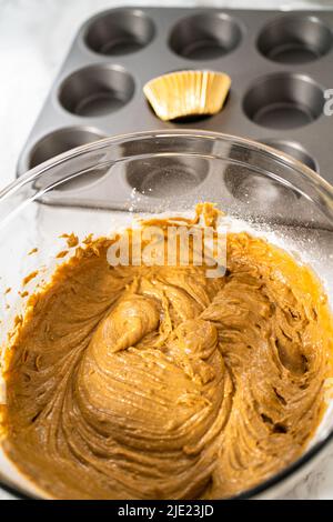 Scooping cupcake batter with a dough scoop into cupcake foil