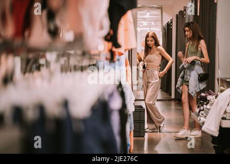 Two pretty girls standing in the store near the changeing room Stock Photo