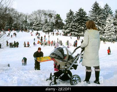 Snow scene in Central Park, New York City. People sledding and having fun after a heavy snowfall on Cedar Hill. Winter landscape  of Park activities Stock Photo