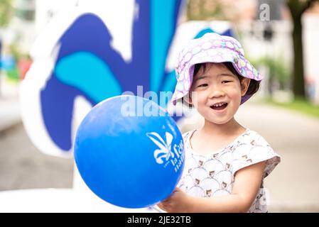 Montreal, Canada - June 24 2022: Little girl waving the Quebec ballon in Quebec day Parade in Montreal downtown Stock Photo