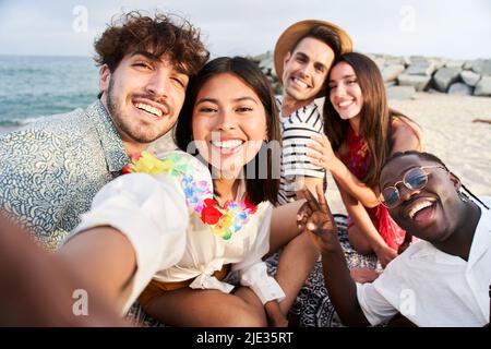 Sunset beach - Group of five cheerful young friends taking selfie portrait. Happy people looking at the camera smiling. Concept of community, youth Stock Photo