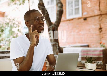 Inspired, smiling multicultural, mix raced man indexing and pointing up, getting new ideas. Studying online, e-learning Stock Photo