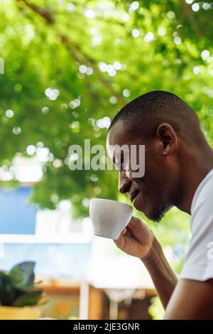 Confident and successful multiracial businessman drinking coffee and work, chatting online using laptop in street cafe Stock Photo