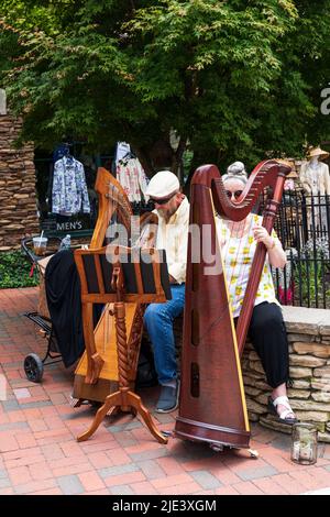 BLOWING ROCK, NC, USA-20 JUNE 2022: Senior man and woman busking with small harps on Main Street. Stock Photo