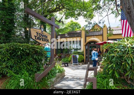 BLOWING ROCK, NC, USA-20 JUNE 2022: The  Town Tavern, showing entrance and customers through rhododendron. Stock Photo