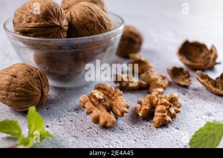 Selective focus on walnuts in a bowl and kernels on white background Stock Photo