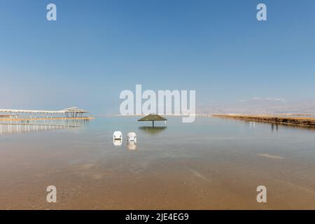 canopy from the sun and two chairs in the water of the dead sea in Israel Stock Photo