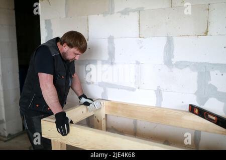 Man assembling table in building under construction Stock Photo