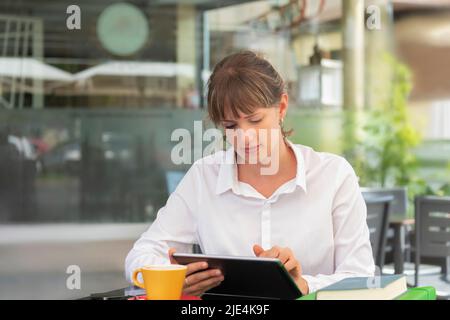 Young businesswoman enjoying coffee and using her tablet Stock Photo