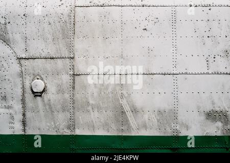 front view closeup of old airplane metallic hull fuselage plating with rows of bolts and rivets industrial texture Stock Photo