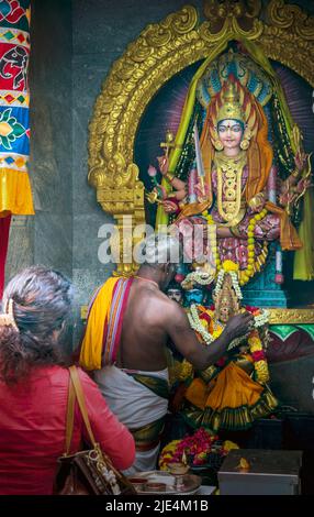 A priest and a worshipper in front of deities in the Sri Veeramakaliamman Temple, Serangoon Road, Little India, Republic of Singapore.  This Hindu tem Stock Photo