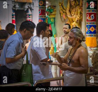 A priest and worshippers in the Sri Veeramakaliamman Temple, Serangoon Road, Little India, Republic of Singapore.  This Hindu temple is one of the old Stock Photo