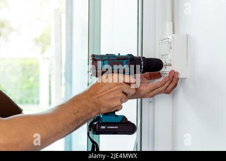 Install the power sockets and switches in the outlet box on the wall with a cordless hand drill. Stock Photo