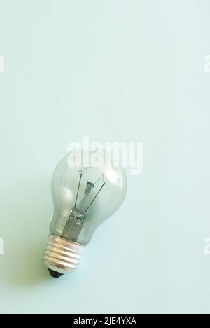 Traditional style glass light bulb with burnt tungsten on blue background. Stock Photo