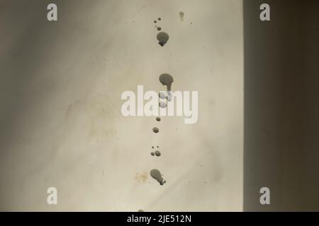 Black drops on white wall. Dirt on white. Wall is unpainted. Splashes on surface. Stock Photo