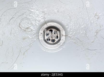 Dirty wash hand basin showing grungy drain with bits of hair Stock Photo