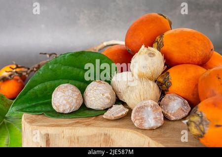 Betel nut or areca nut with betel leaf isolated on wooden background. Stock Photo