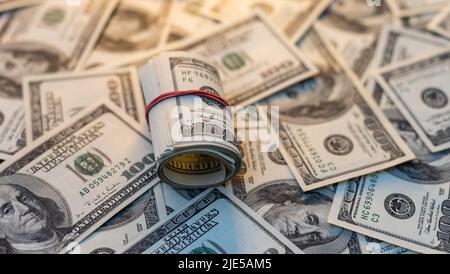 A roll of money tightened by an elastic band close-up macro shot. Usd money wad, bundle of usa cash. Several American dollar bills rolled and tied up Stock Photo