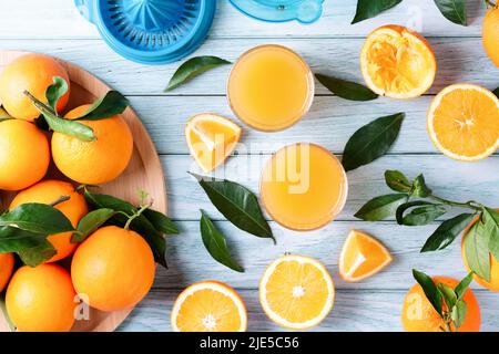 Fruit squeezer and ripe fresh oranges on blue wooden table top, fresh orange juice making, overhead Stock Photo