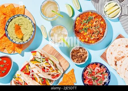 Mexican food table with traditional dishes. Chili con carne, tacos, tomato salsa, corn chips with guacamole Stock Photo
