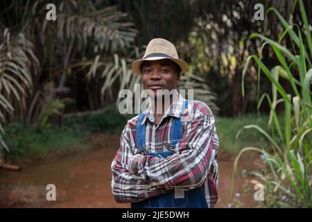 Portrait of a farmer posing outdoors with folded arms, smiling successful African businessman. Stock Photo