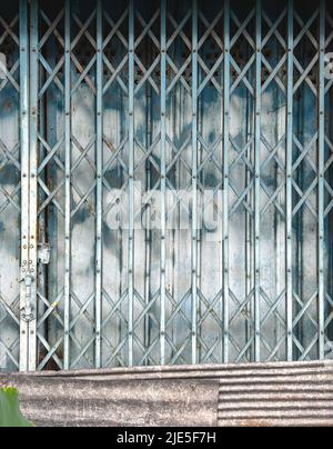 Gate folding. folding metal gate with lock and zinc, galvanized reparing panels of the building, vintage style building folding gate. Stock Photo