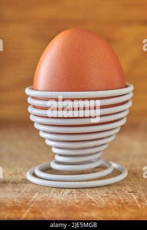 One boiled egg in a spiral-shaped metal support on wood background Stock Photo