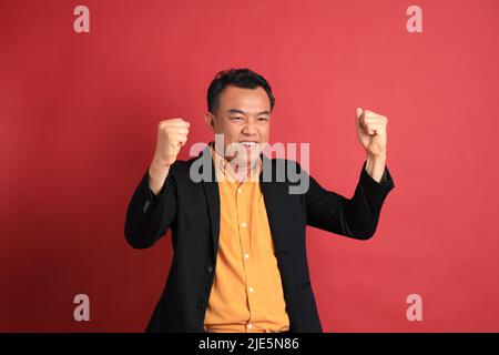 The Asian middle aged man standing on the red background. Stock Photo